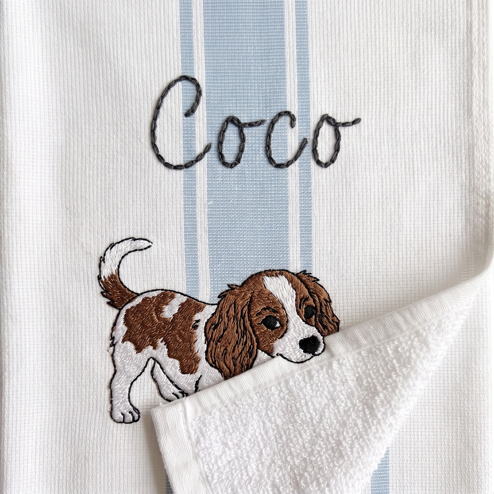 Example Cavalier King Charles Spaniel embroidery named Coco on the light blue stripe towel